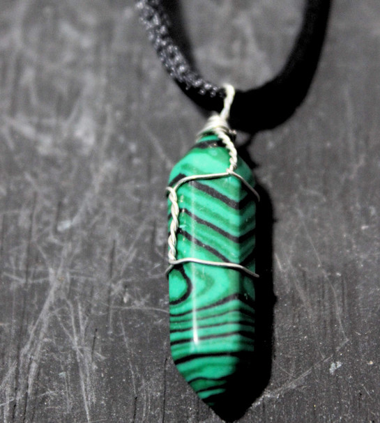 photo of a wire wrapped malachite crystal point on a wood background