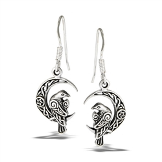 photo of a pair of sterling silver earrings in the shape of ravens perched on a crescent moon on a white background