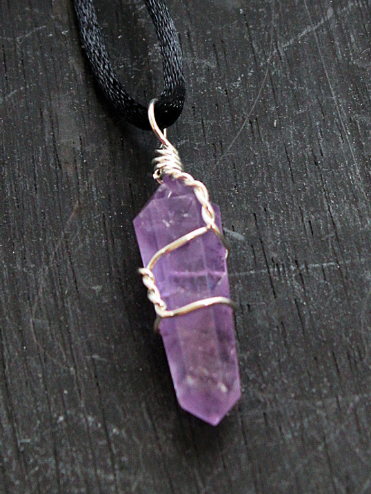 photo of a wire wrapped amethyst crystal point on a wood background