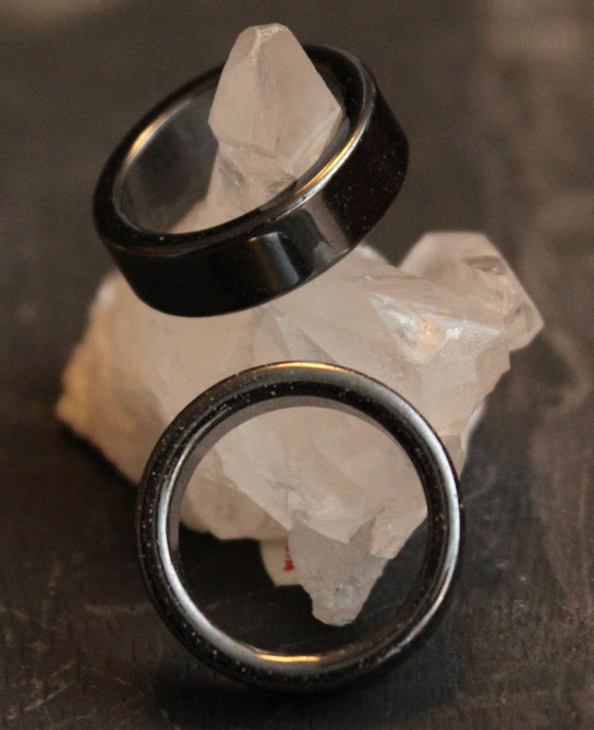 hematite band rings shown leaning against a quartz crystal