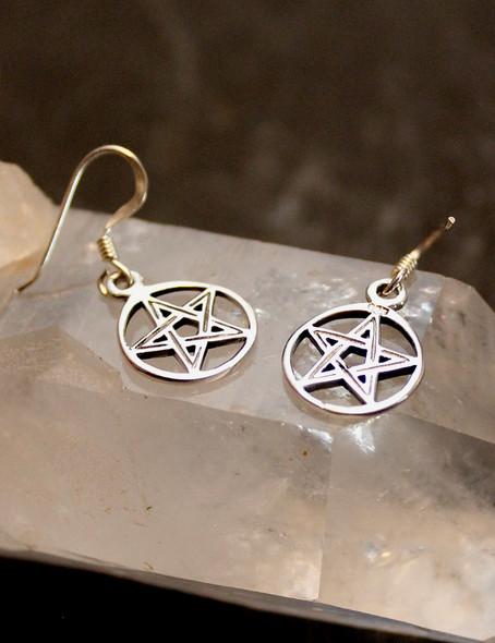 photo of a pair of sterling silver pentagram earrings resting on a quartz crystal 