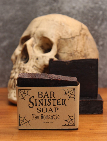 two bars of bar sinister new romantic scented dark burgundy colored soap, propped in front of a lifesize skull