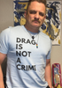 LGBTQ+ activist smiling while wearing a “Drag Is Not a Crime” tee during a peaceful protest.