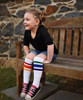 Young child standing tall in rainbow socks, showing LGBTQ+ pride through play