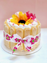 Cathy's classic holiday design for Mother's Day. Featuring lady fingers around the cake wrapped like a package with a bow and non-edible silk flowers on top.