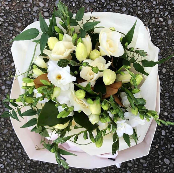 Fresh white and green scented seasonal blooms arranged in a carry bag. 