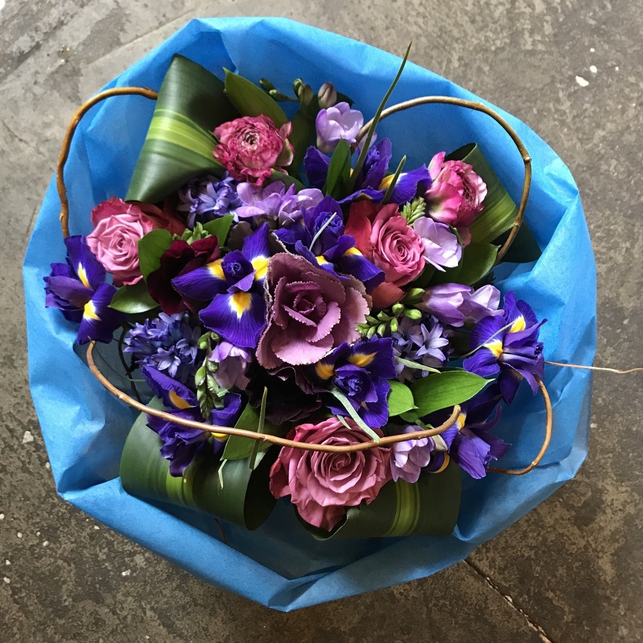 Seasonal purples and blues in a hand tied roll wrapped bouquet.