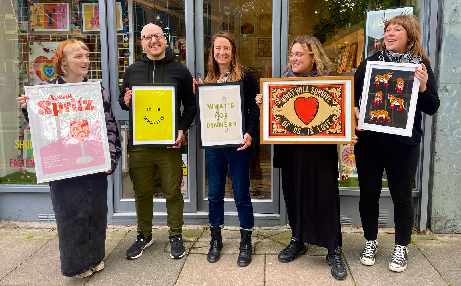 East End Prints team stood outside their Brick Lane Showroom holding their favourite art prints