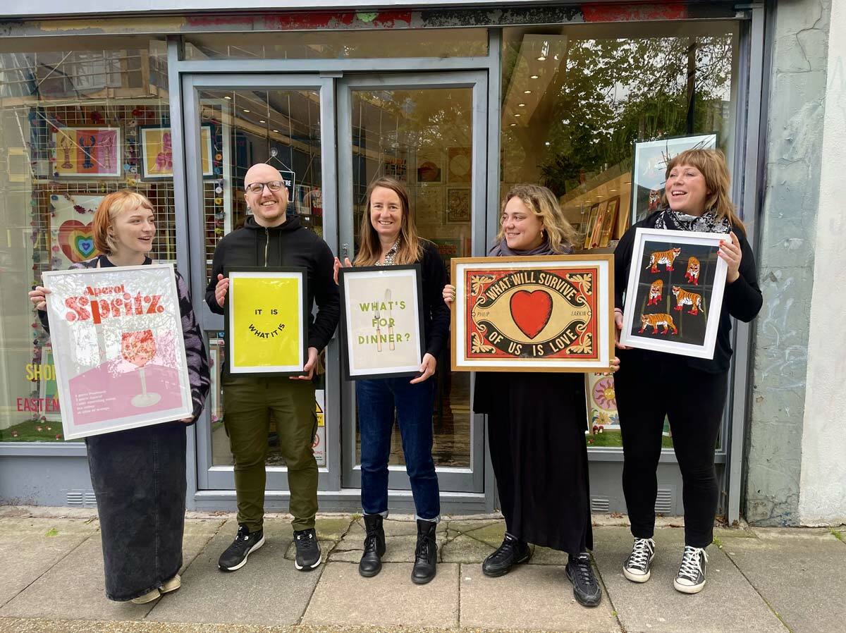 East End Prints team stood outside their Brick Lane Showroom holding their favourite art prints