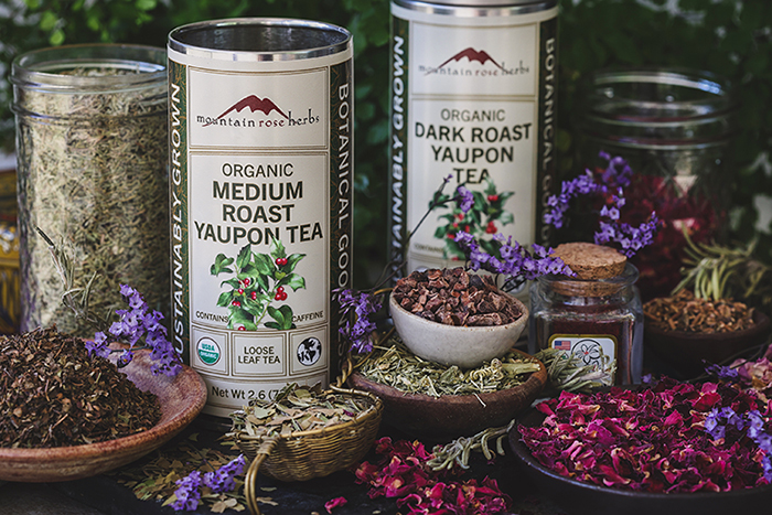Two tins of yaupon tea surrounded by other herbs. 