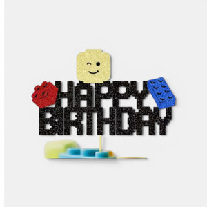 Lego-inspired Happy Birthday glitter cake topper with colourful building block decorations and smiling character face