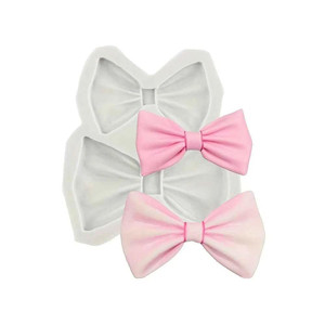 Large Silicone Bow Mould, a silicone mold with two pink bow-shaped cavities used for baking or crafting. Large Silicone Bow Mould, a silicone mold with two pink bow-shaped cavities used for baking or crafting.