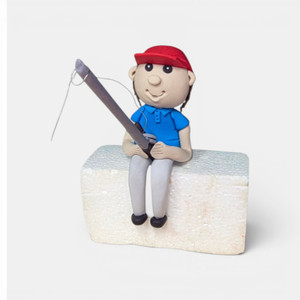 The Cake Mixer Handmade Fondant Fishing Cake Decorations, a fondant sculpture of a boy fishing on a kayak with ducks and a fishing rod.