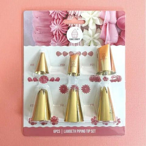 Cake Craft Lambeth Piping Tip Set, six gold-colored piping tips arranged in a plastic holder with pink and white decorative icing in the background. Cake Craft Lambeth Piping Tip Set, six gold-colored piping tips arranged in a plastic holder with pink and white decorative icing in the background.