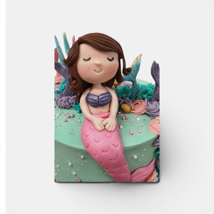 Handmade gumpaste mermaid cake topper sitting on a pastel mermaid themed birthday cake