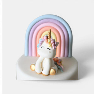 Handmade gumpaste unicorn and rainbow cake topper set featuring a white unicorn with pastel mane, gold horn and pastel rainbow backdrop.