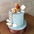 Aeroplane Teddy Bear Cake Decorating Set, decorative cake featuring a teddy bear pilot sitting on an airplane atop a blue frosted cake with clouds and gold stars.