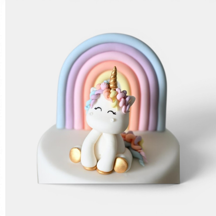 Handmade gumpaste unicorn and rainbow cake topper set featuring a white unicorn with pastel mane, gold horn and pastel rainbow backdrop.
