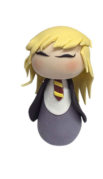Handmade Hermione Granger gumpaste cake topper with long hair, Hogwarts-style robes and red and gold tie.