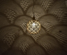 Moroccan style brass bedside lamp suspended as a pendant light, ideal for boho bedrooms with artisan character.