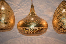 Handmade brass pendant lights hanging over kitchen bar