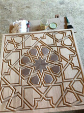 Eight-point star wood inlay medallion panel in walnut and oak, in progress on a workshop bench