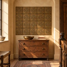 Trinity Cross Knot in hand-embossed brass, as a wall panel above a wooden chest of drawers on a stair landing