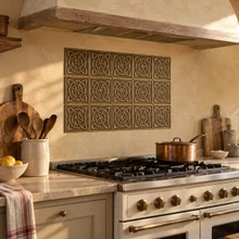 Four Loop Circle Knot Celtic knot tiles in hand-embossed brass, as a backsplash panel above a gas range under a timber hood
