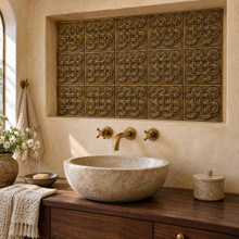 Eternity Knot Celtic knot tiles in hand-embossed brass, lining a plastered niche above a stone basin vanity in a bathroom