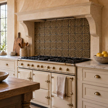 Open Square Weave Knot in hand-embossed brass, as a backsplash panel inside a plaster range hood alcove in a kitchen