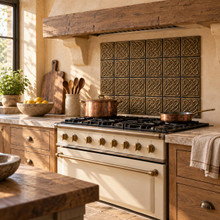 Open Square Weave Knot in hand-embossed brass, as a backsplash panel behind a cream range under a timber hood