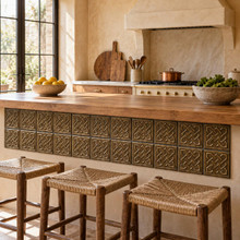 Open Square Weave Knot in hand-embossed brass, set into the front panel of a kitchen island with rush stools