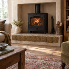 Double Loop Circle Knot in hand-embossed brass, as a band along the raised wood stove hearth in a living room