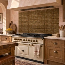 Quartered Circle Knot in hand-embossed brass, as a full backsplash under a plaster hood behind a cream range