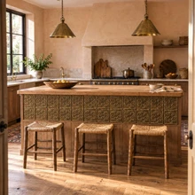 Six Ring Flower Knot Celtic knot tiles in hand-embossed brass, set into the front panel of a kitchen island with rush stools