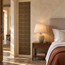 Framed Cross Knot Celtic knot tiles in hand-embossed brass, as a tall vertical panel beside a bed in a bedroom