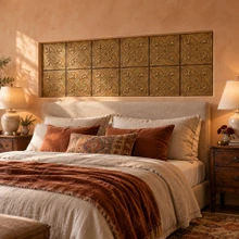 Hand-embossed solid brass fleur-de-lis tiles in aged bronze as a feature wall behind the headboard in a bedroom