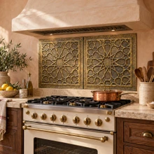 Hand-embossed solid brass Andalusian star tiles in aged bronze, 20 inch panels installed on the kitchen wall behind a range