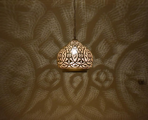 Moroccan dome pendant light fixture designed for bedrooms or cozy living spaces, casting patterned shadows with boho flair.