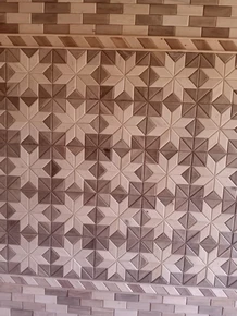 Tri-tone gradient star and diamond wood mosaic wainscot panel with herringbone chevron border, installed on a stairwell wall