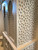 Carved bathroom vanity cabinet — arched lattice door with brass hardware
