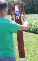 Man using delineator driver to drive delineator post into ground.