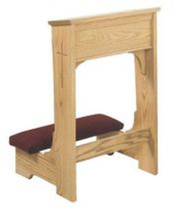 A red kneeling pad connected to a wooden, rectangular shelf with a cross on the side.
 