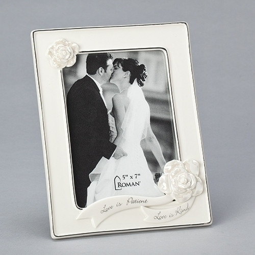 8.75"H White Porcelain Wedding or Anniversary Photo Frame adorned with decorative flowers and the words Love is Patient and Love is Kind on banners across the bottom of the frame.  Frame holds 5" x 7" photo. Frame is made of porcelain and measures 8.75"H X 6.75"W X .75"L.