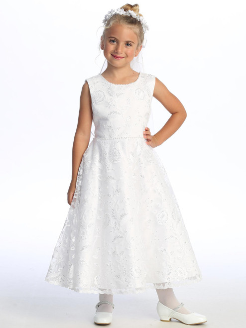 Little girl smiling in a white Communion dress with embroidered tulle.