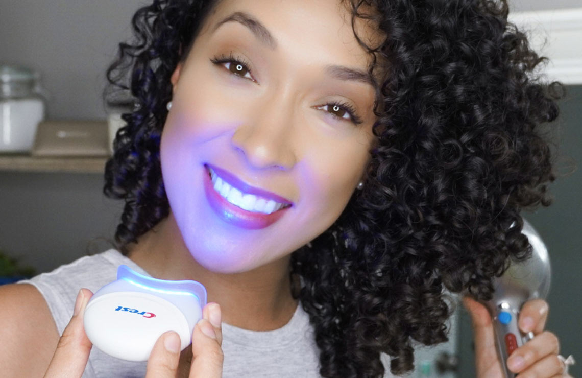 Red haired girl using Crest Blue Light while doing makeup | Crest White Smile