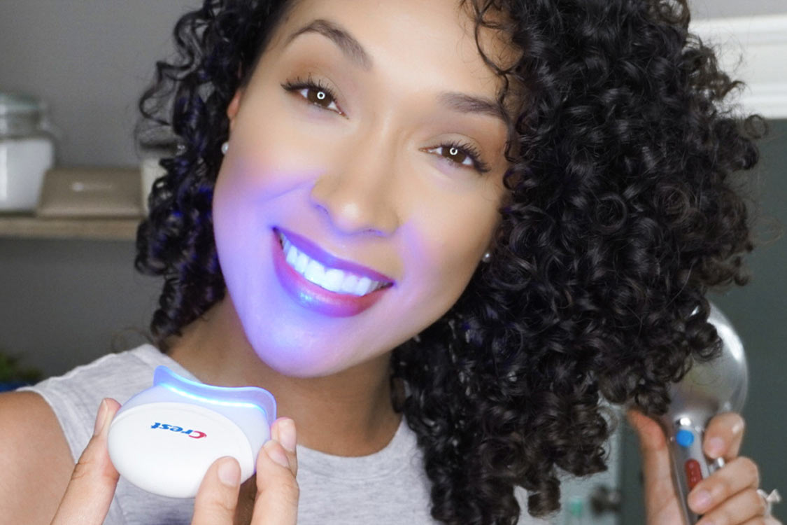 Red haired girl using Crest Blue Light while doing makeup | Crest White Smile