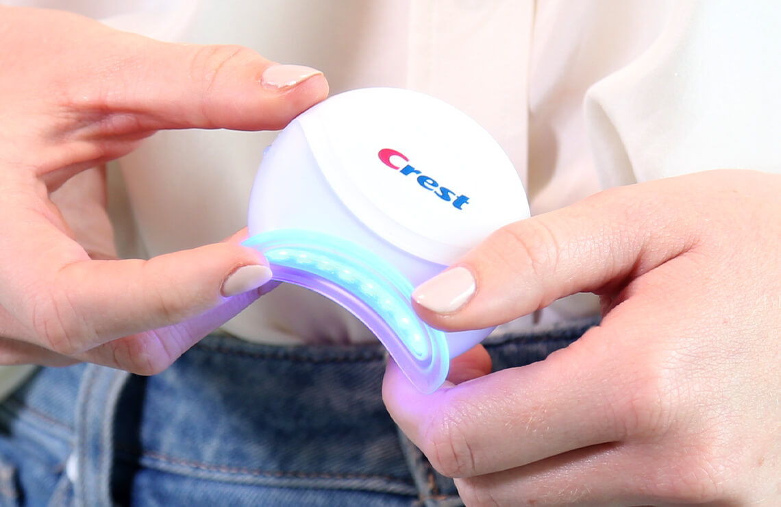 Two hands holding a Crest Blue Light at waist level | Crest White Smile
