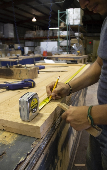 Worker measuring wood in shop