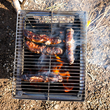 Seek Outside Titanium stove, roaring fire inside cooks food on the Grill Top upgrade